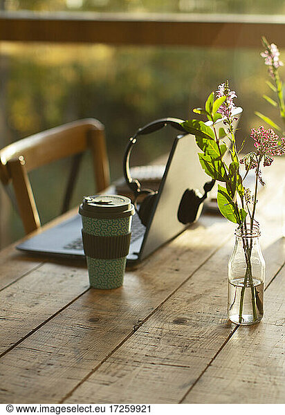 Laptop  coffee and simple wildflower bouquet on cafe table