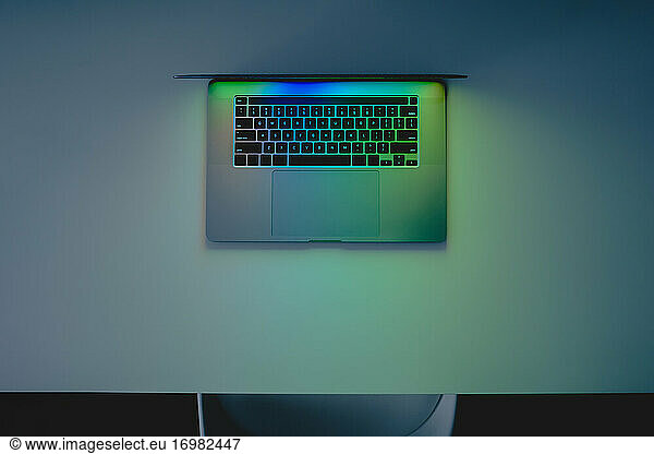 Laptop computer standing on a table  low key blue light image sh