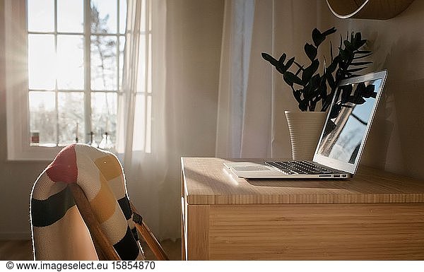 laptop on a desk in a home office with beautiful window light