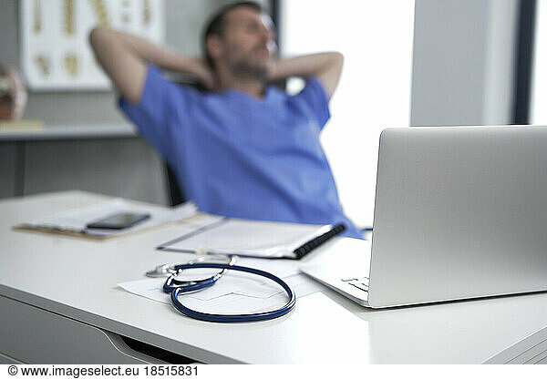 Laptop on desk with doctor relaxing in background