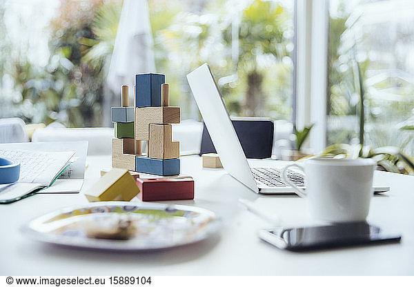 Laptop on dining table with building blocks and dishes