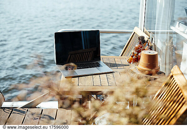 Laptop on wooden table at houseboat on sunny day
