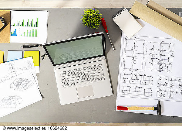 Laptop und verschiedene architektonische Werkzeuge  Entwürfe und Pläne liegen auf dem Schreibtisch im Atelier