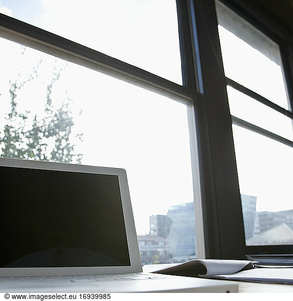Laptop vor einem Fenster mit Blick auf die städtische Skyline.