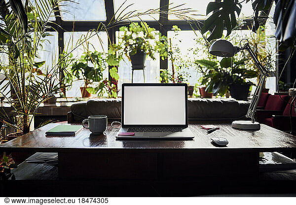Laptop with blank screen on desk at loft office