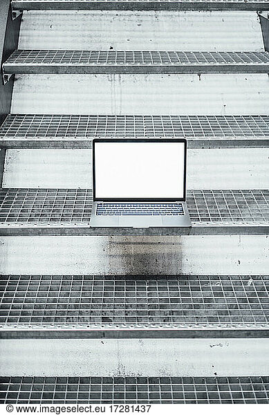 Laptop with blank screen on steps in factory