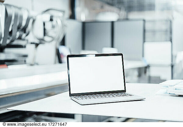 Laptop with blank screen on table in industry