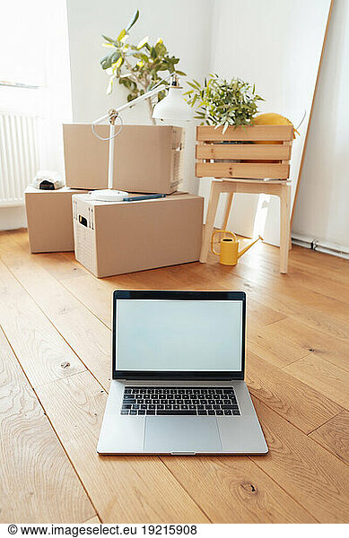 Laptop with cardboard boxes on floor at home