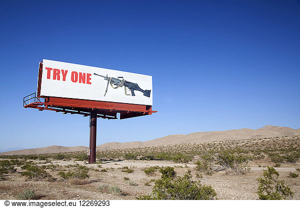 Large board advertising machine gun in the desert.