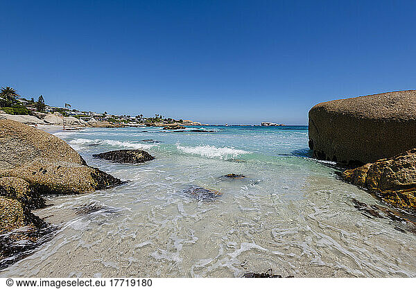 Large boulders frame the view of beachfront homes along the rocky shore at Clifton Beach on the Atlantic Ocean; Cape Town Western Cape South Africa