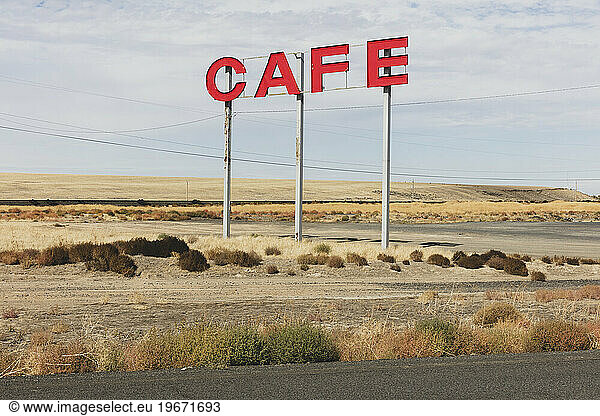 Large CAFE sign over rural farmland.