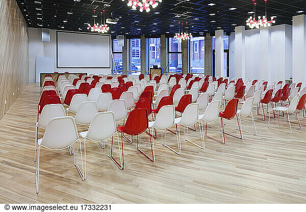 Large empty room with red and white chairs in rows