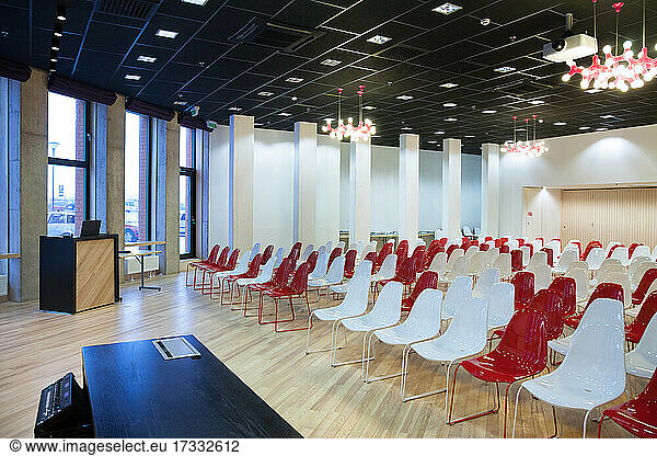 Large empty room with red and white chairs in rows