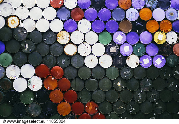 Large pile of colorful petroleum barrels stacked up in colour co-ordinated way.