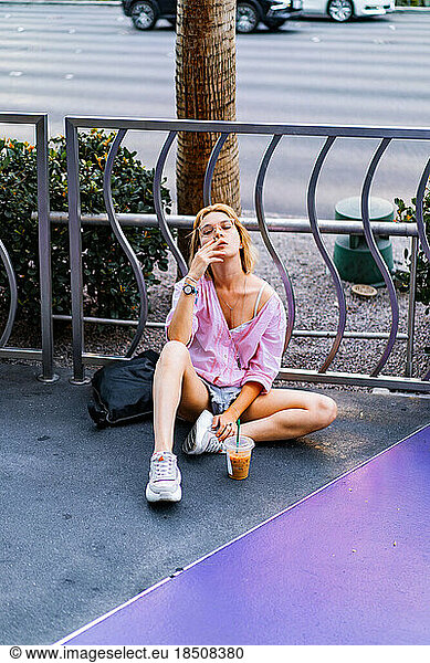 Las Vegas. girl sits on the sidewalk  smokes  drinks coffee