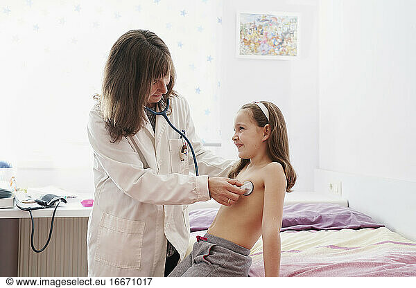 lateral view of a pediatric doctor examine little happy girl wit