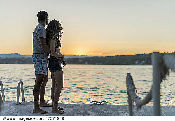 Latin couple watching the sunset sunrise at the summer lake