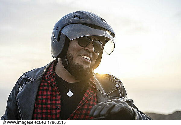 Latin man motorcyclist look the desert at sunset.