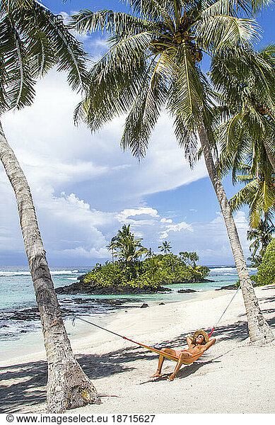 Latin man  with straw hat  tanning on hammock under palm trees  Samoa