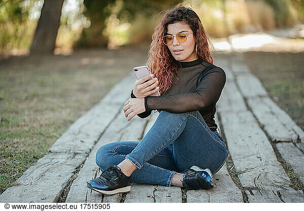 latin woman with glasses look at your mobile phone outdoors