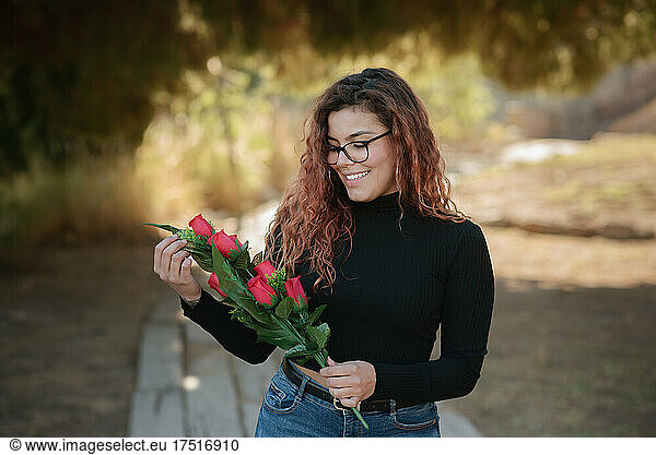 Latin woman with glasses looks lovingly at the roses