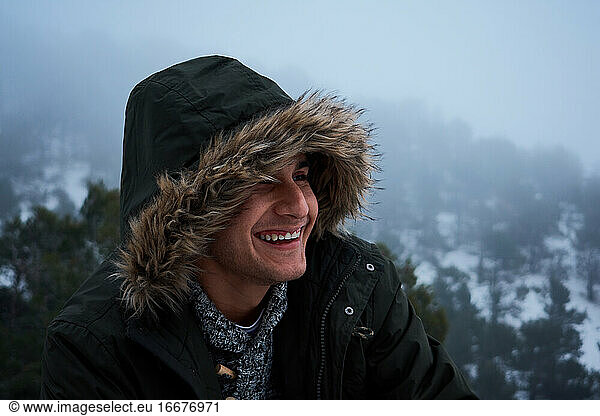 Latin young man smiles in a coat on a snowy day