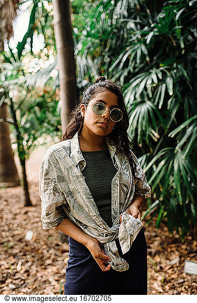 Latina girl with green glasses and green shirt surrounded by leaves