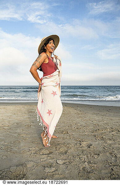 Latina woman having fun at the beach with towel and hat