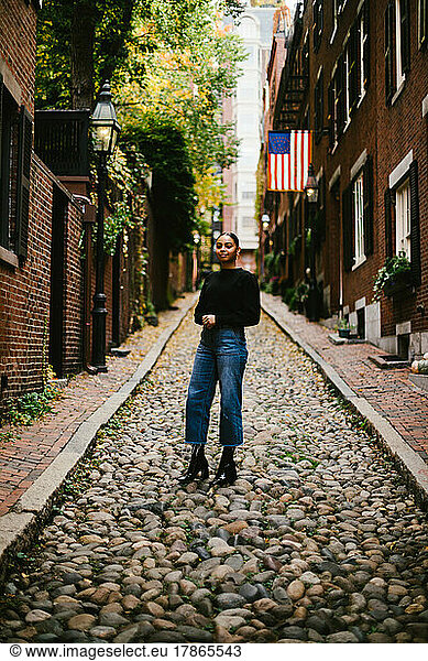 Latina woman on cobblestone street brick townhomes and American flag