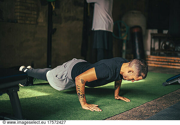 Latino boy doing push-ups in his home gym