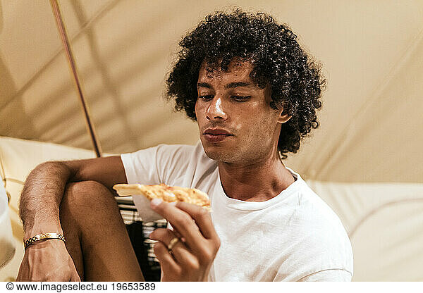 latino man with but afro eating pizza