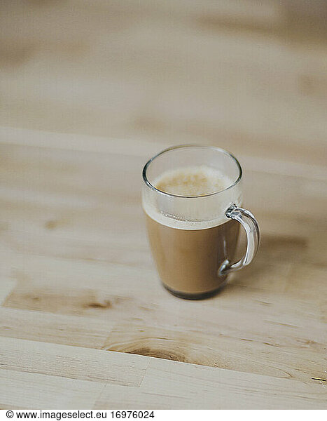 Latte with espresso coffee in glass mug on wooden table