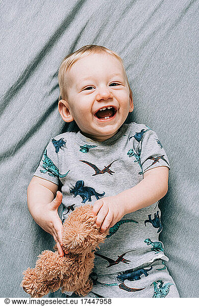 Laughing Baby Boy Holding Teddy Bear with Cute Teeth