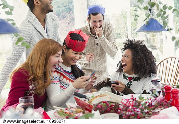Laughing friends wearing paper crowns at Christmas dinner