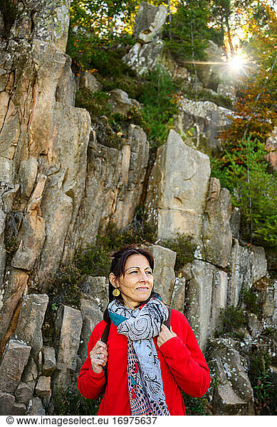 Laughing hiker woman with scarf and backpack  against stone formation
