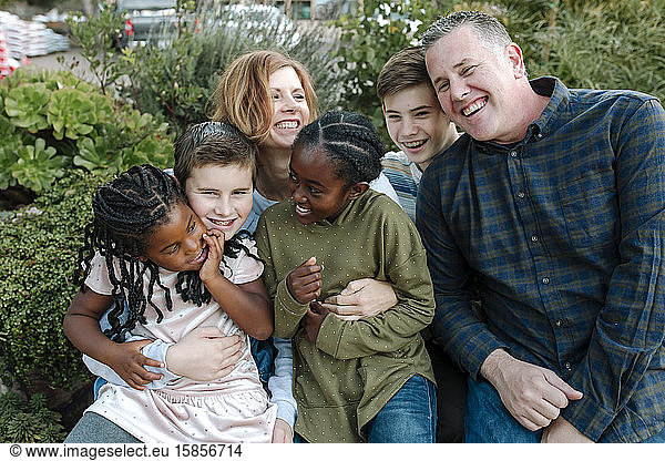Laughing joyful multiracial family outdoors in a group hug