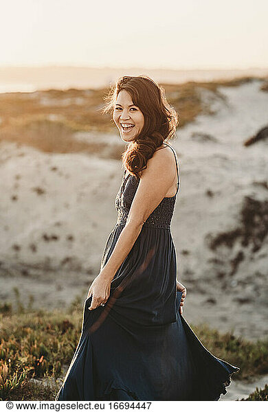 Laughing mid-40's beauty with long dark hair on sand dune