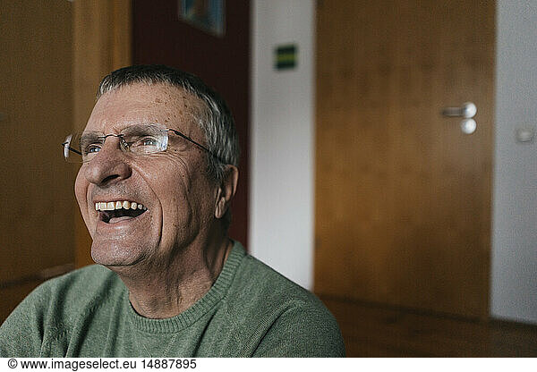 Laughing senior man at home looking away
