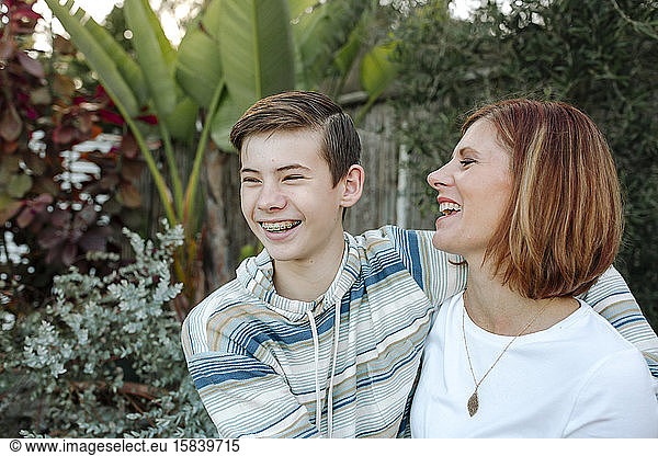 Laughing teen boy with braces hugging mid-40's mom