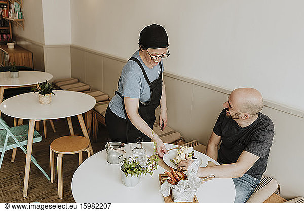 Laughing waitress serving food in a coffee shop