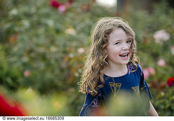 Laughing 3 yr old girl exudes joy outdoors in garden