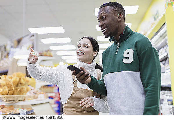 Lebensmittelhändlerin hilft Kunden im Supermarkt