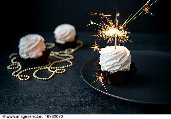 Leckere Cupcakes mit Wunderkerze auf dunklem Hintergrund