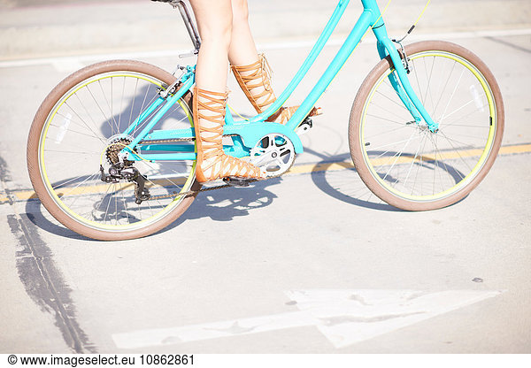 Legs and strappy sandals of young female cyclist at Venice Beach  Los Angeles  California  USA