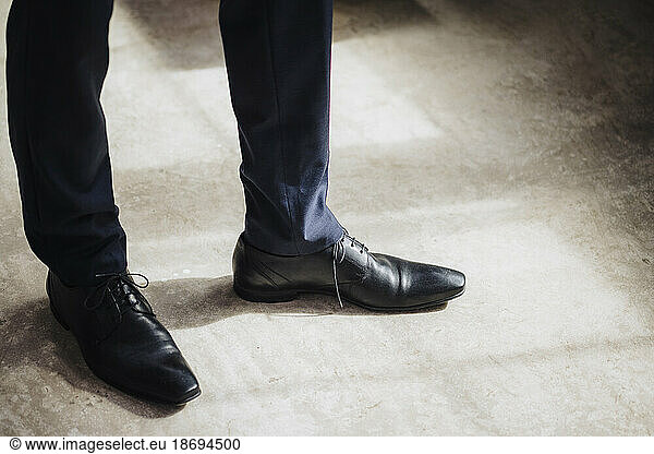 Legs of businessman wearing black formal shoes standing in factory