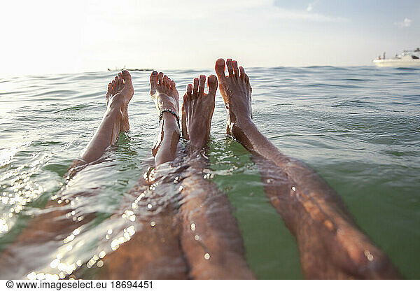Legs of couple floating in sea