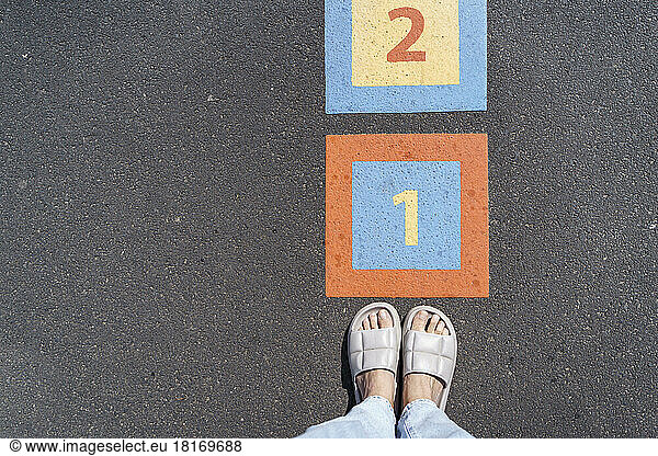 Legs of woman by number on footpath