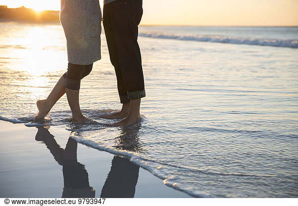 Legs of young couple standing on beach