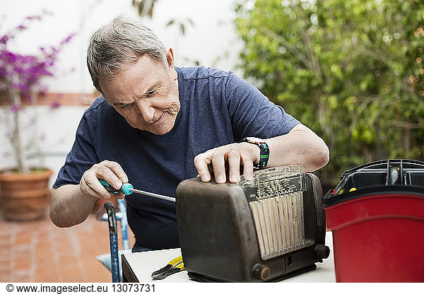 Leitender Mann repariert altmodisches Radio auf dem Hof