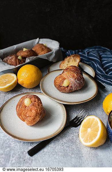 Lemon filled cruffins on stone counter with plates and forks.